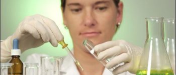 Frau im Labor hält Reagenzglas in der Hand.