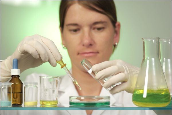 Frau im Labor hält Reagenzglas in der Hand.