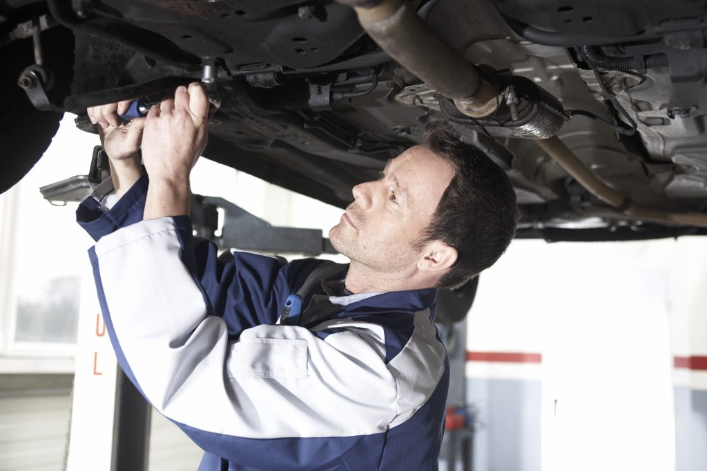 Man in Autowerkstatt schraubt