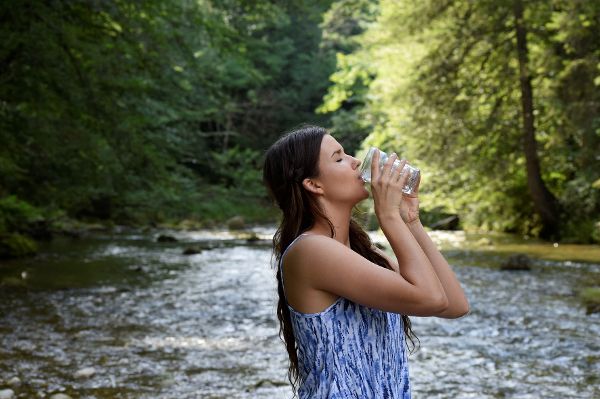 Frau trinkt am Fluss.