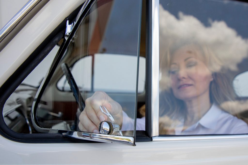 Frau als Fahrerin öffnet Dreiecksfenster in altem Auto.