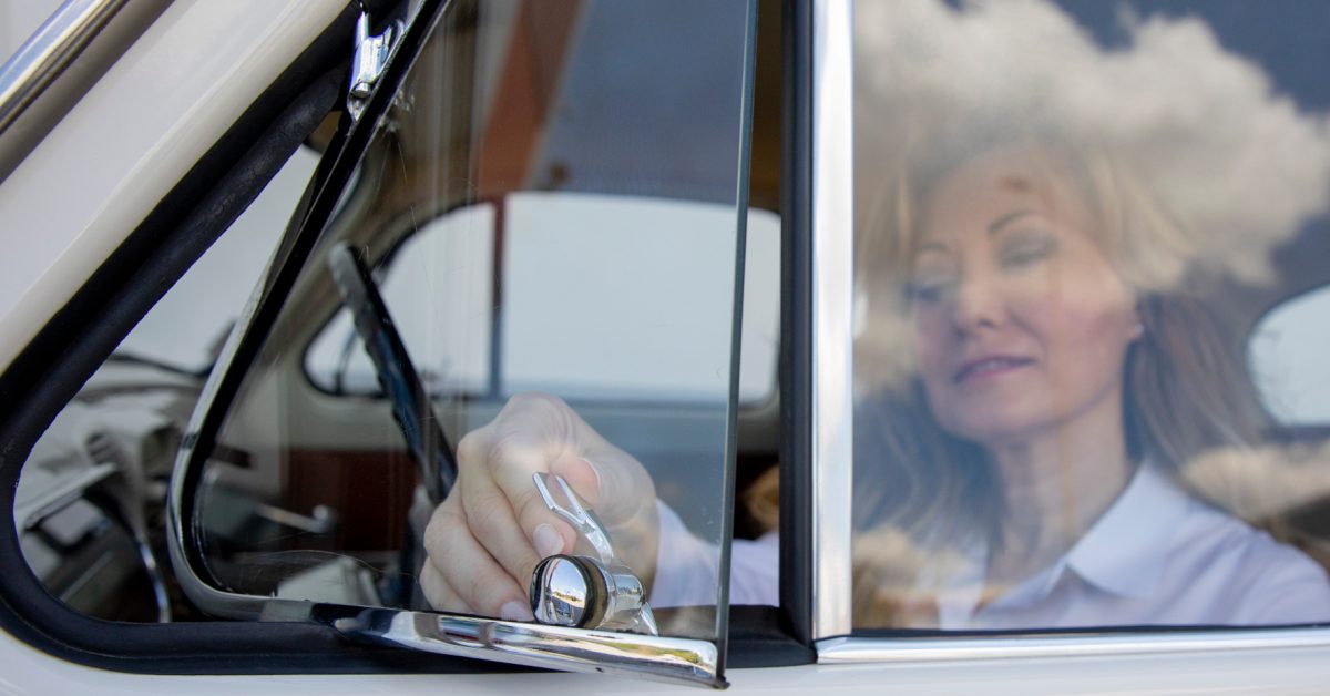 Frau als Fahrerin öffnet Dreiecksfenster in altem Auto.