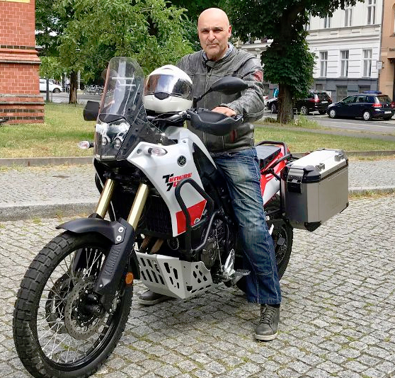 Motorradfahrer mit weißem Held auf dem Tank sitzt auf weißem Motorrad