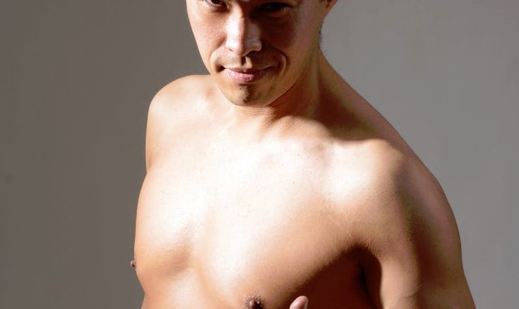 Mann mit freiem Oberkörper streckt Daumen und Finger.