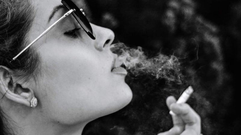 Frau mit brennender Zigarette von der Seite.