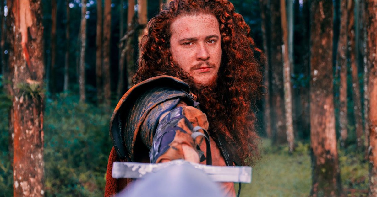 Mann mit gezogenem Schwert im Wald.