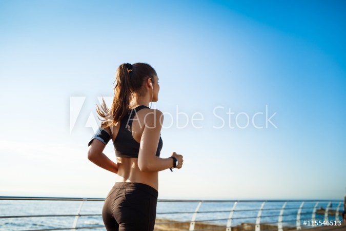 Picture of young attractive fitness girl jogging with sea on background