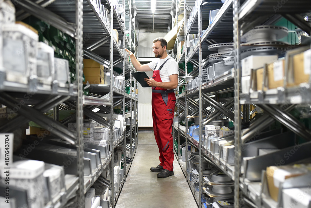 Mitarbeiter im Lager mit KFZ-Ersatzteilen in einer Autowerkstatt // Employees in the warehouse with spare parts for cars in a garage