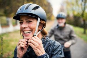 Active senior couple with electrobikes standing outdoors on a road in nature.
