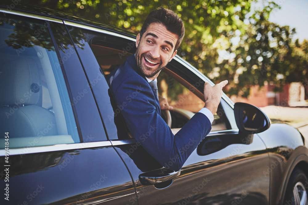 Im on my way to work buddy. Shot of a cheerful young businessman hanging out of a car window and pointing with his hand towards the front of his car.
