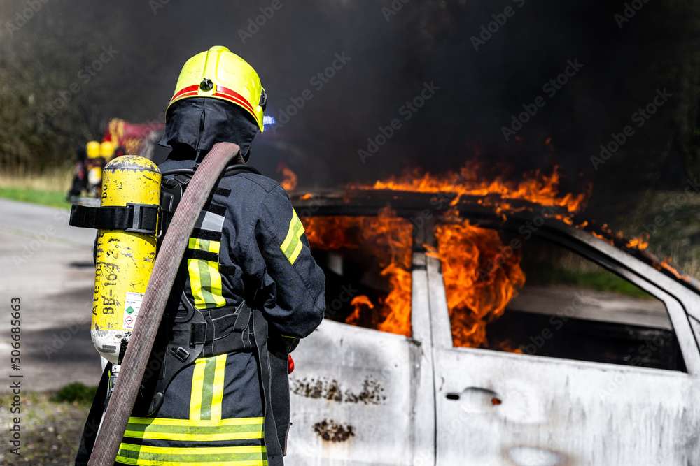 Feuerwehrmänner löschen ein brennendes Auto