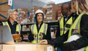 Female warehouse manager having a discussion with her team during a staff meeting in a logistics center