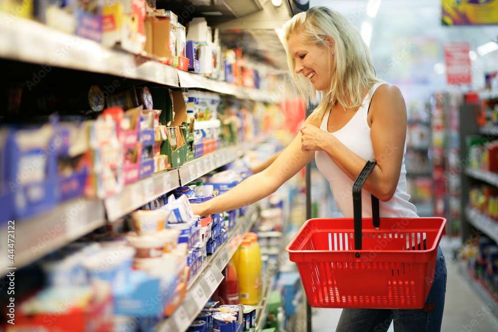 Frau mit rotem Einkaufskorb im Supermarkt