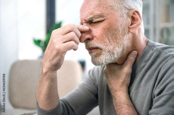 sick mature man feeling unwell and touching nose bridge