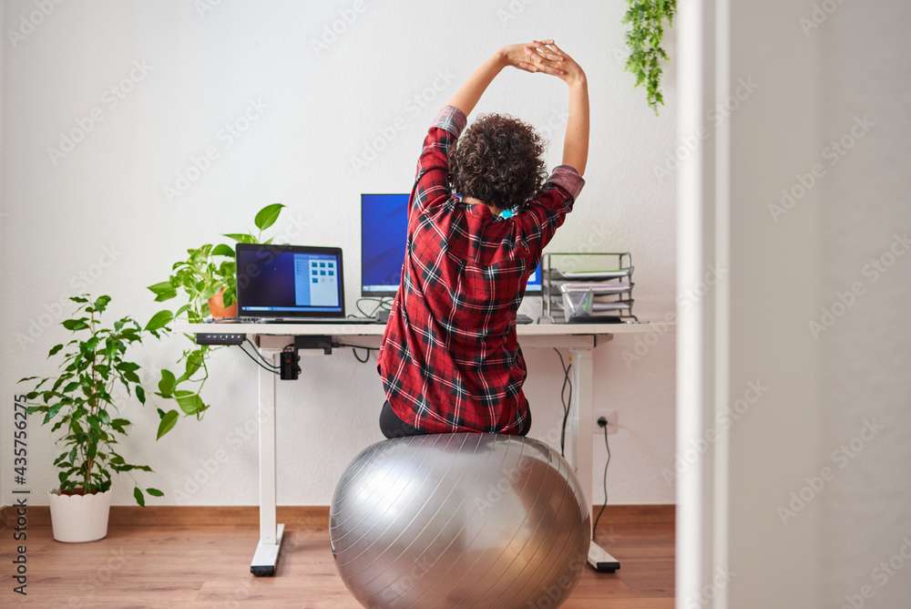 Woman stretches while working out sitting on a fitball