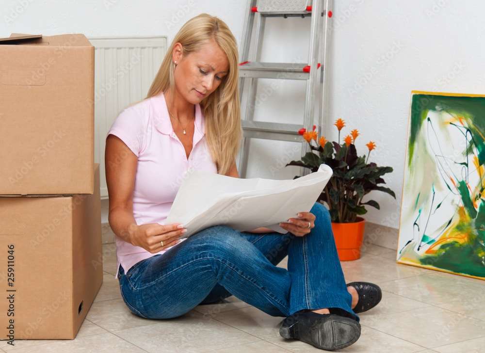 Frau mit Plan in neuer Wohnung beim Umzug.